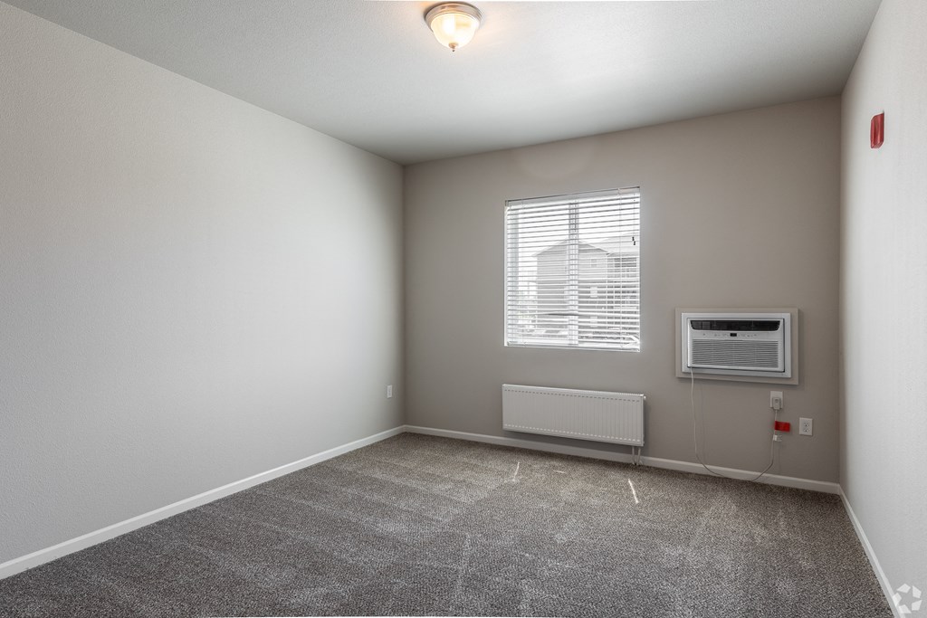 an empty room with a window and an air conditioner