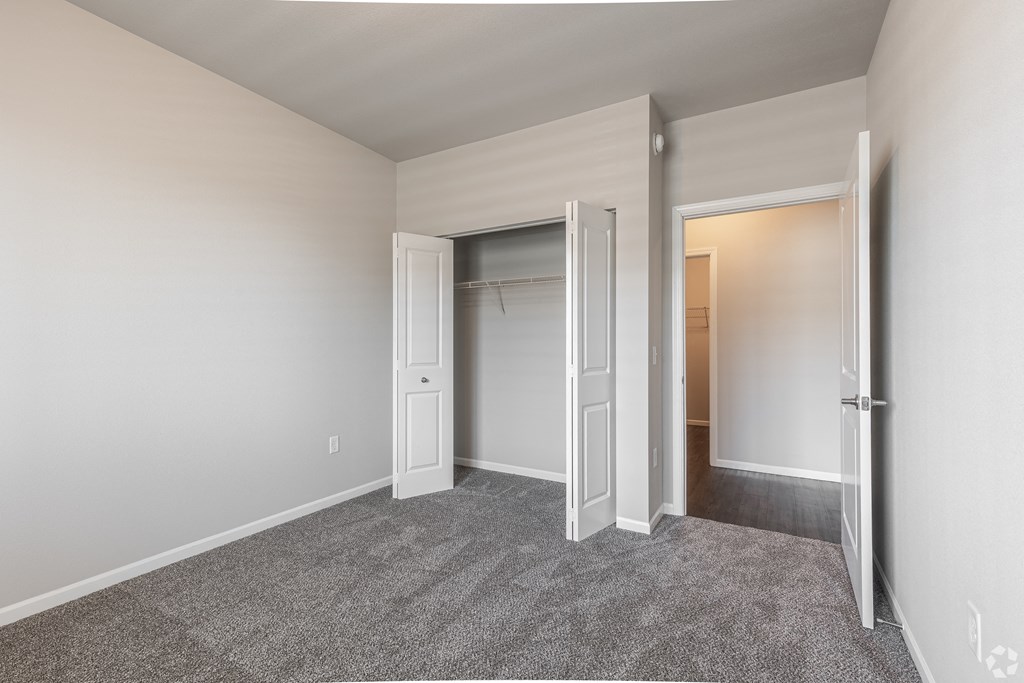 an empty bedroom with a closet and an open door