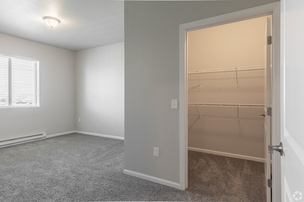 an empty bedroom with a closet and a window