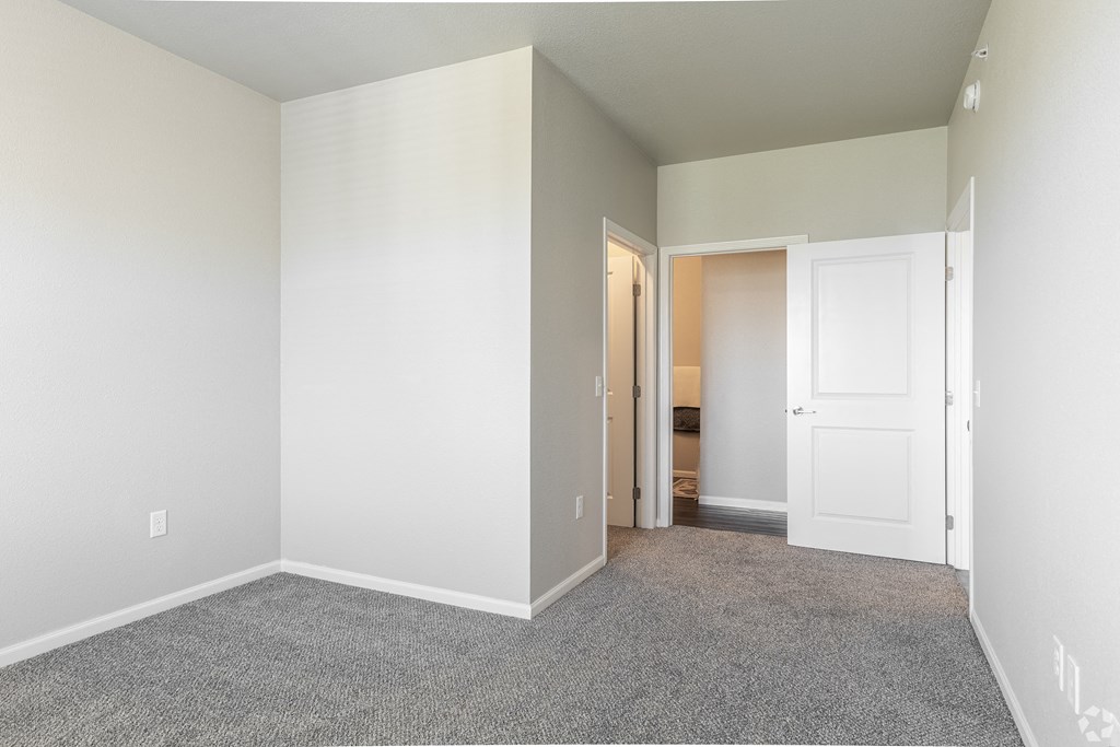 an empty room with carpet and a door to a bathroom