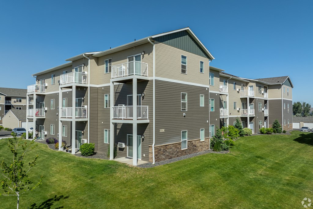 an exterior view of an apartment building with a green lawn