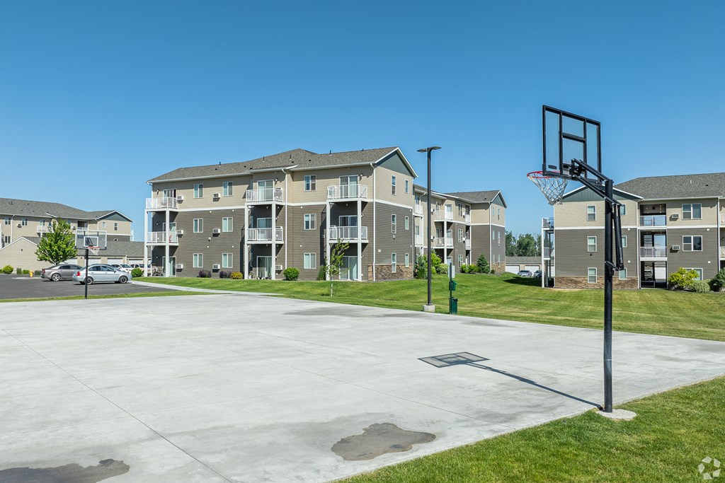 an empty basketball court with an apartment building in the background