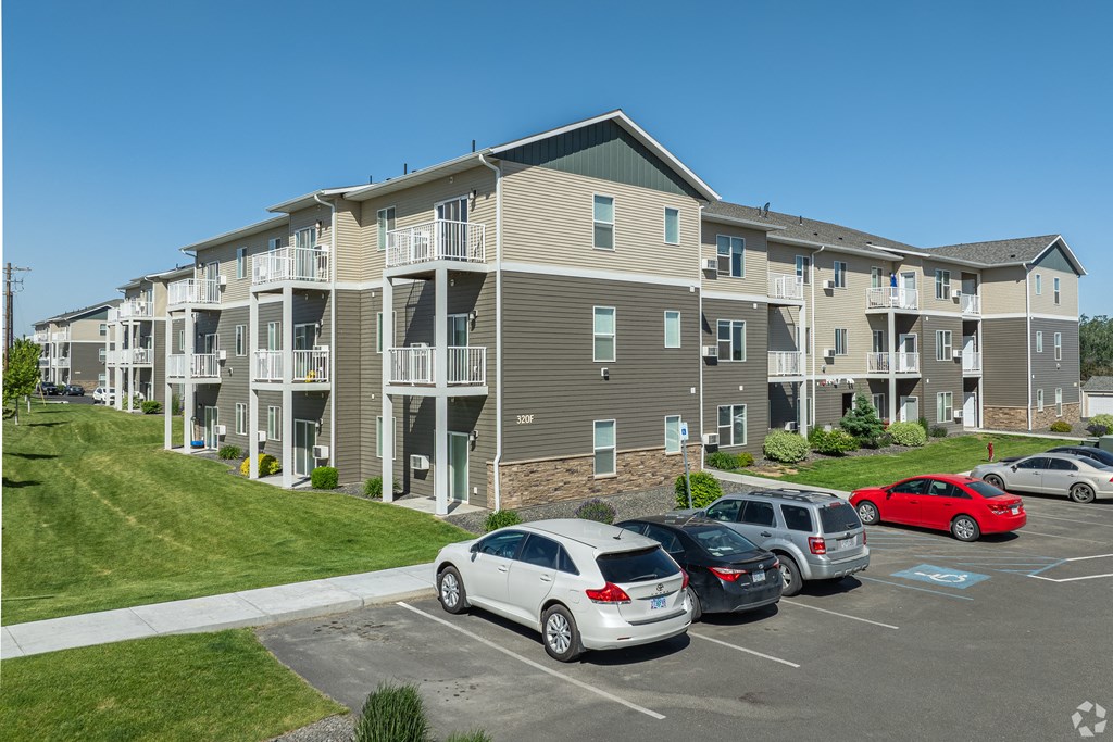 an apartment building with cars parked in a parking lot