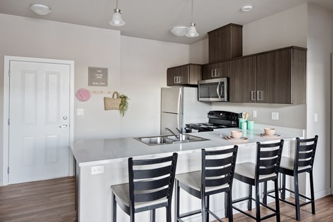 a kitchen with a island and three chairs in front of a sink and a microwave