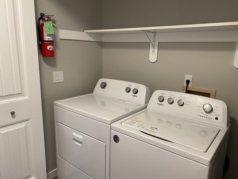 A white dryer and washer sitting next to each other in a laundry room.