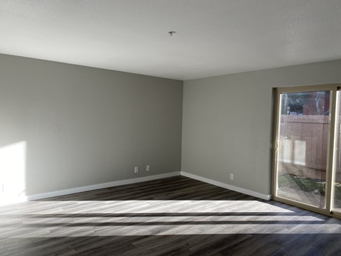 A room with wooden flooring and a sliding glass door.