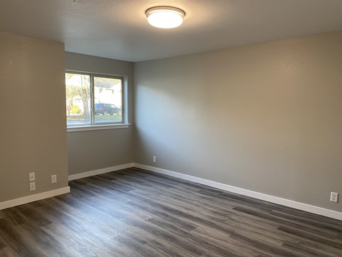 A room with a window and a wooden floor.