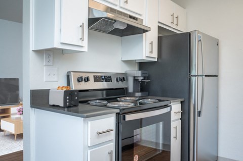 a kitchen with white cabinets and a stove and a refrigerator