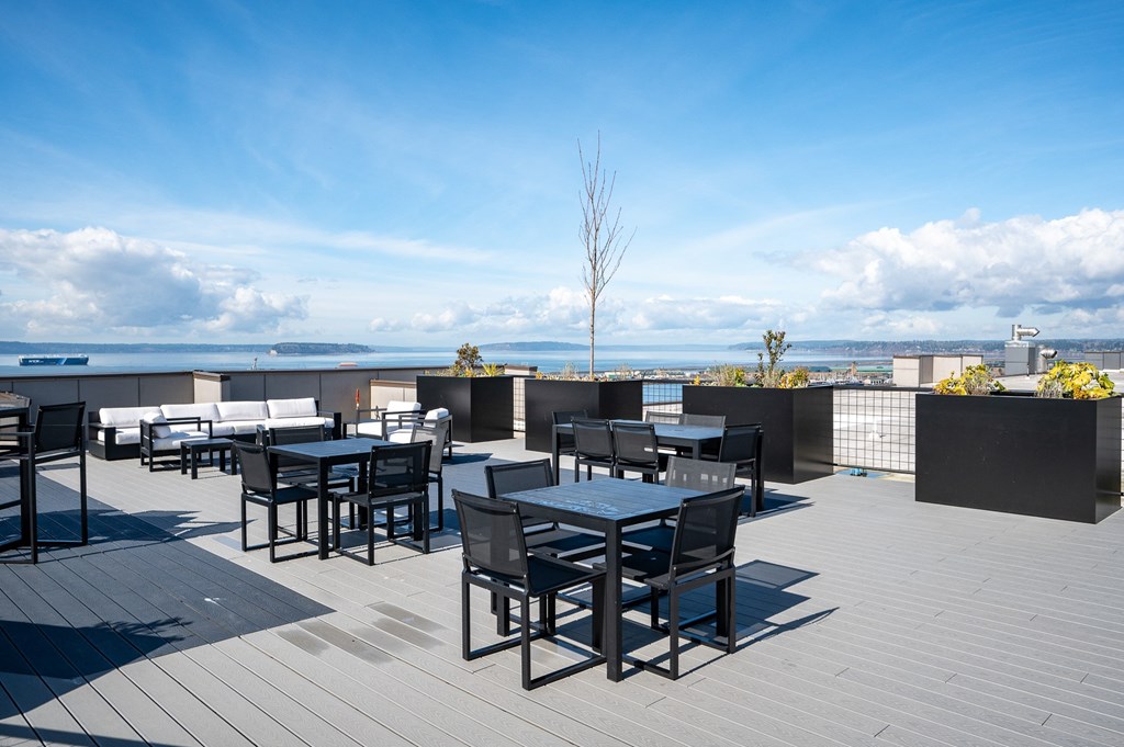 a rooftop patio with tables and chairs overlooking the ocean