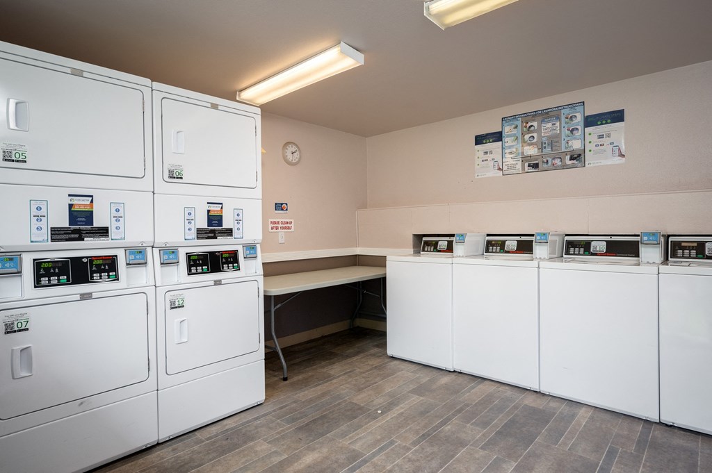 a utility room with a row of white washers and dryers and a counter