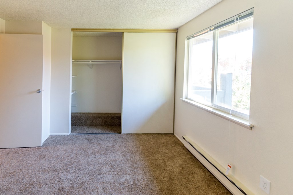 an empty room with a window and a closet