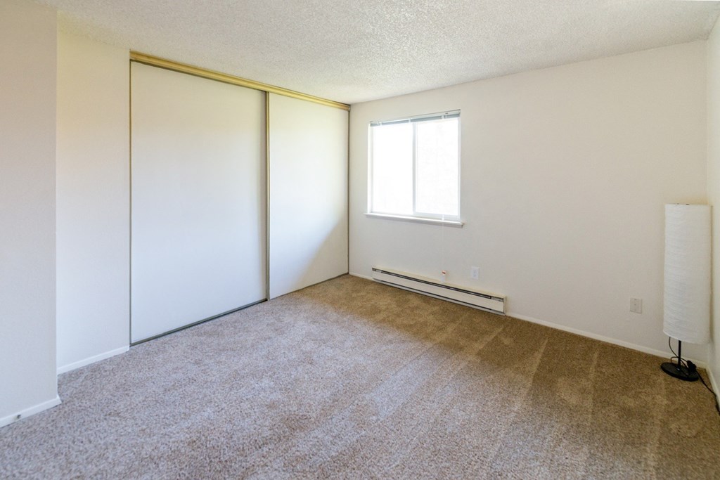 an empty living room with white walls and carpet and a window