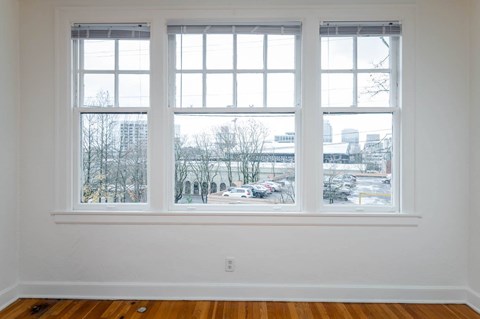 A room with a large window overlooking a parking lot and buildings.