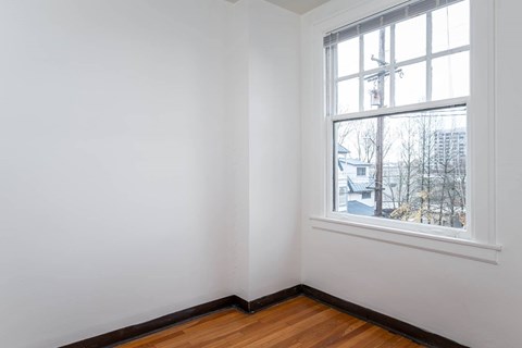 A room with a window and a wooden floor.