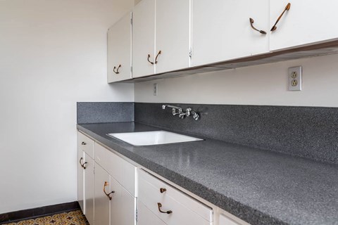 A kitchen with white cabinets and a grey countertop.