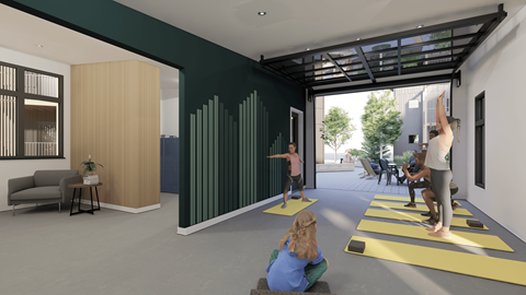 A yoga class is taking place in a room with a green wall and a yoga mat on the floor.