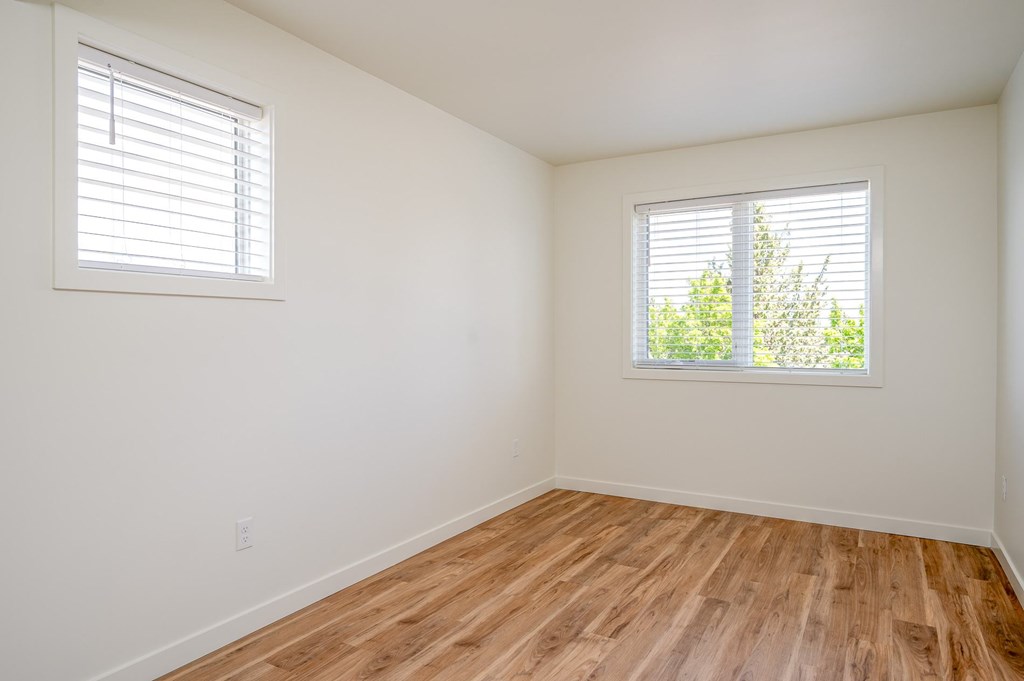 A room with wooden floors and two windows.