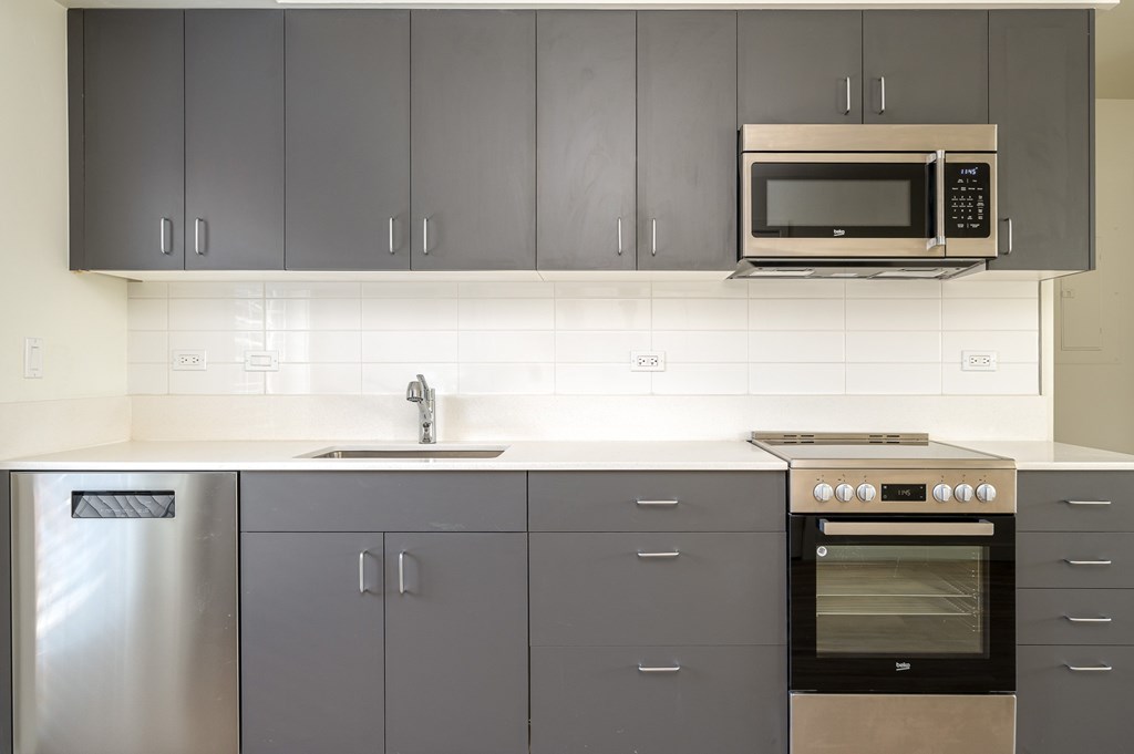 A kitchen with a stainless steel refrigerator, a microwave, and a stove top oven.