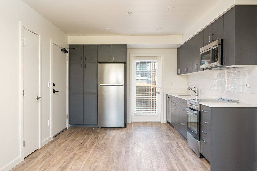 A kitchen with a refrigerator, oven, and microwave.
