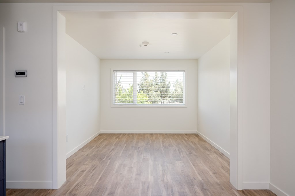 A room with a window and wooden flooring.