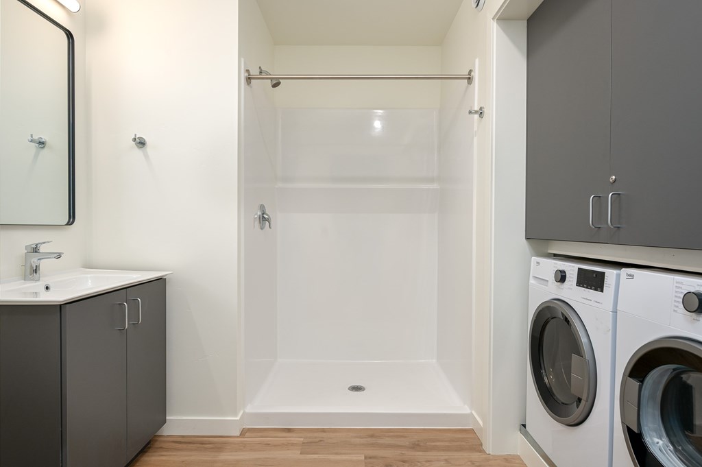 A modern bathroom with a washer and dryer built into the cabinetry.