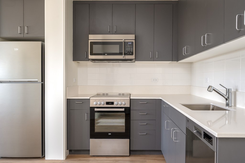 A modern kitchen with a stainless steel refrigerator and a built-in oven.