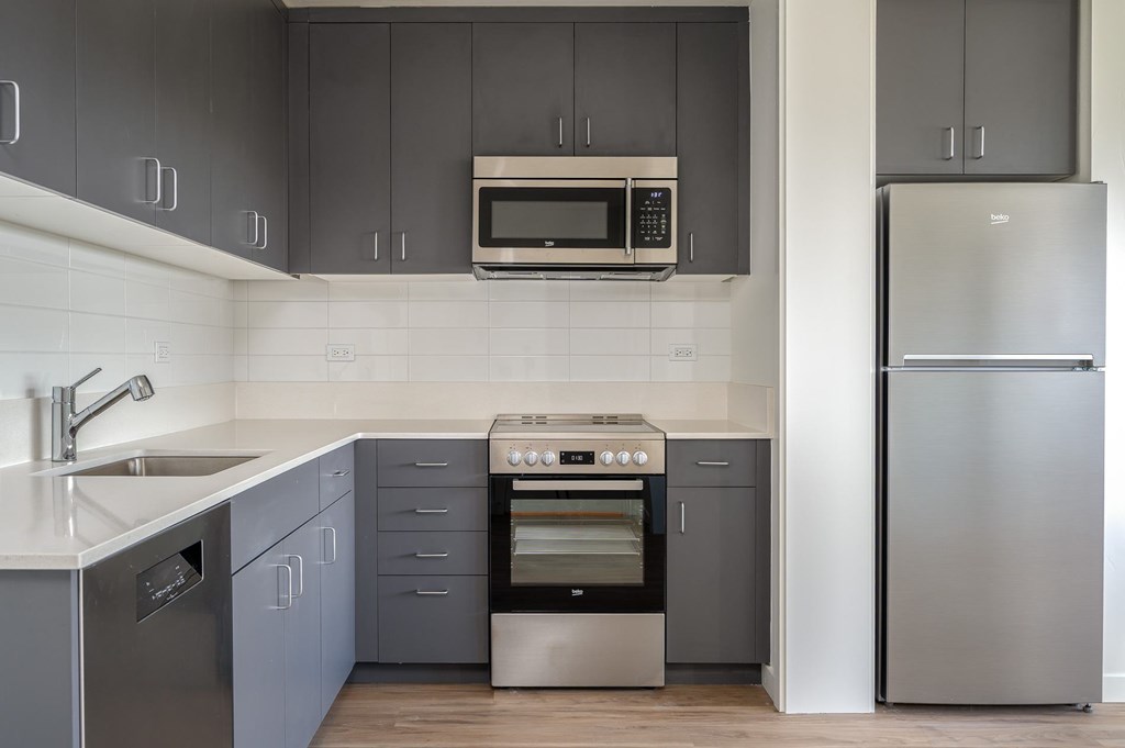 A modern kitchen with a stainless steel refrigerator and a built-in oven.