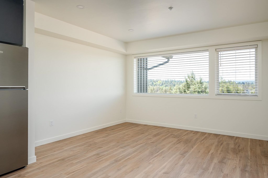 A room with wooden flooring and a window with blinds.