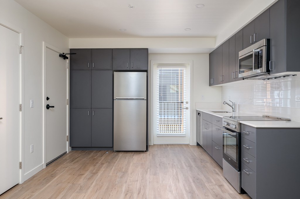 A kitchen with a refrigerator, oven, and microwave.