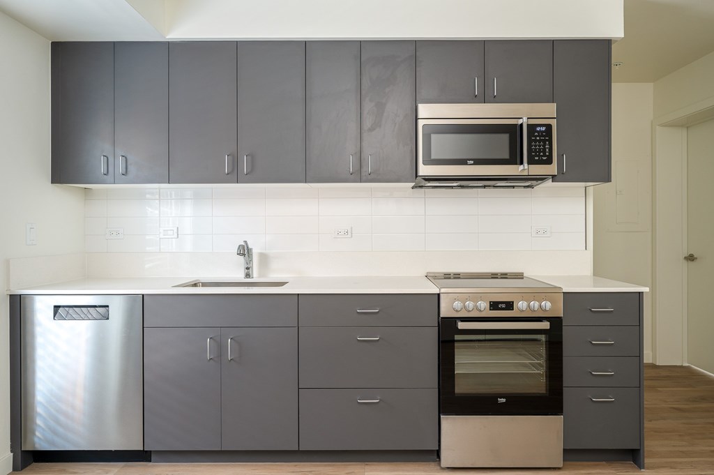 A modern kitchen with a stainless steel refrigerator, a double oven, and a microwave above the sink.