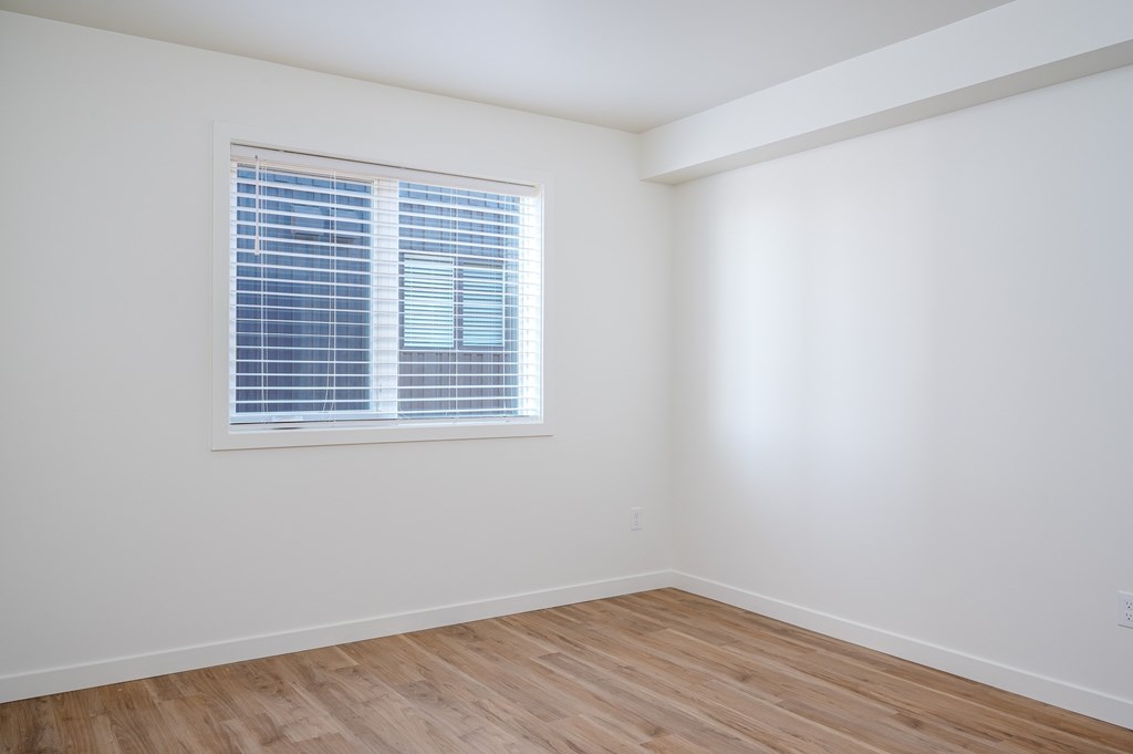 A room with a window and wooden flooring.