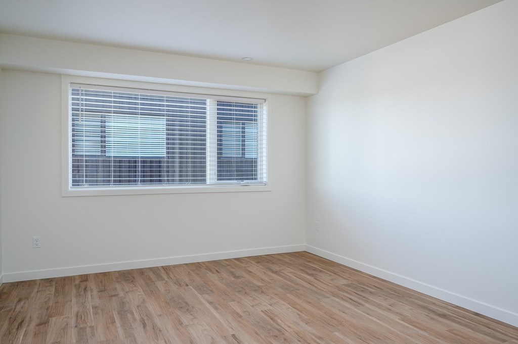 A room with a window and wooden flooring.