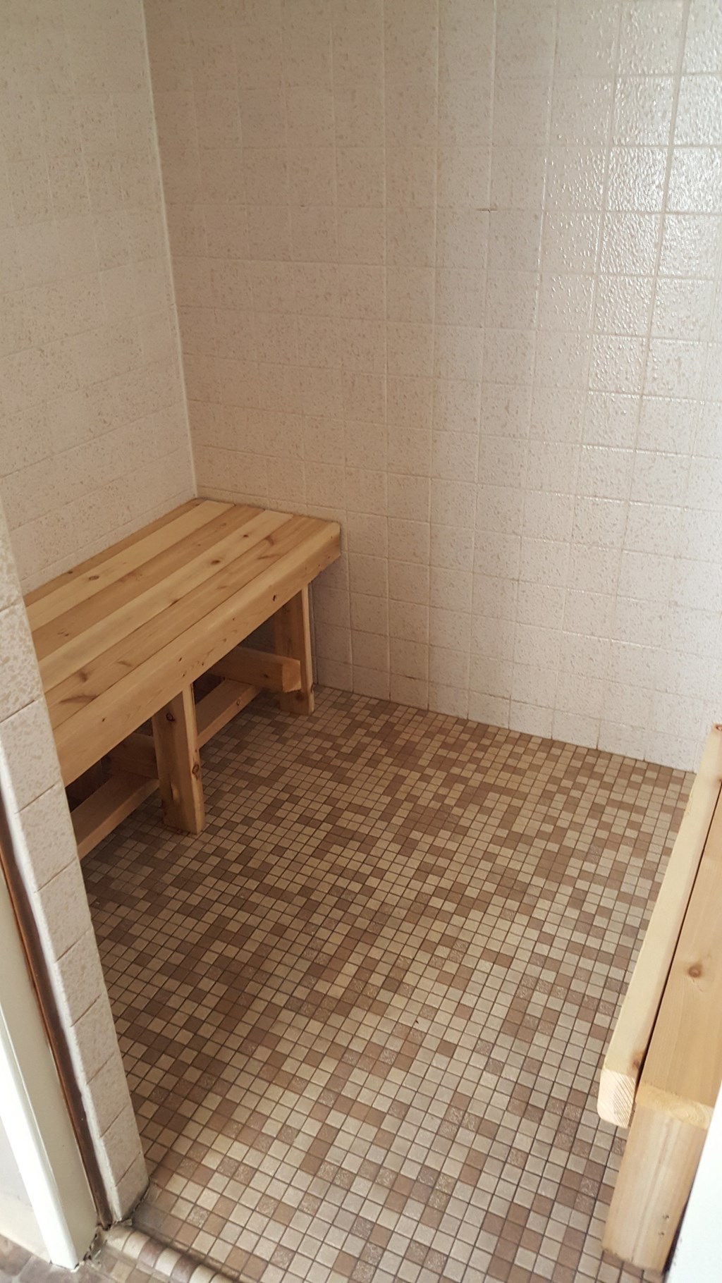 a small room with a wooden bench in a shower