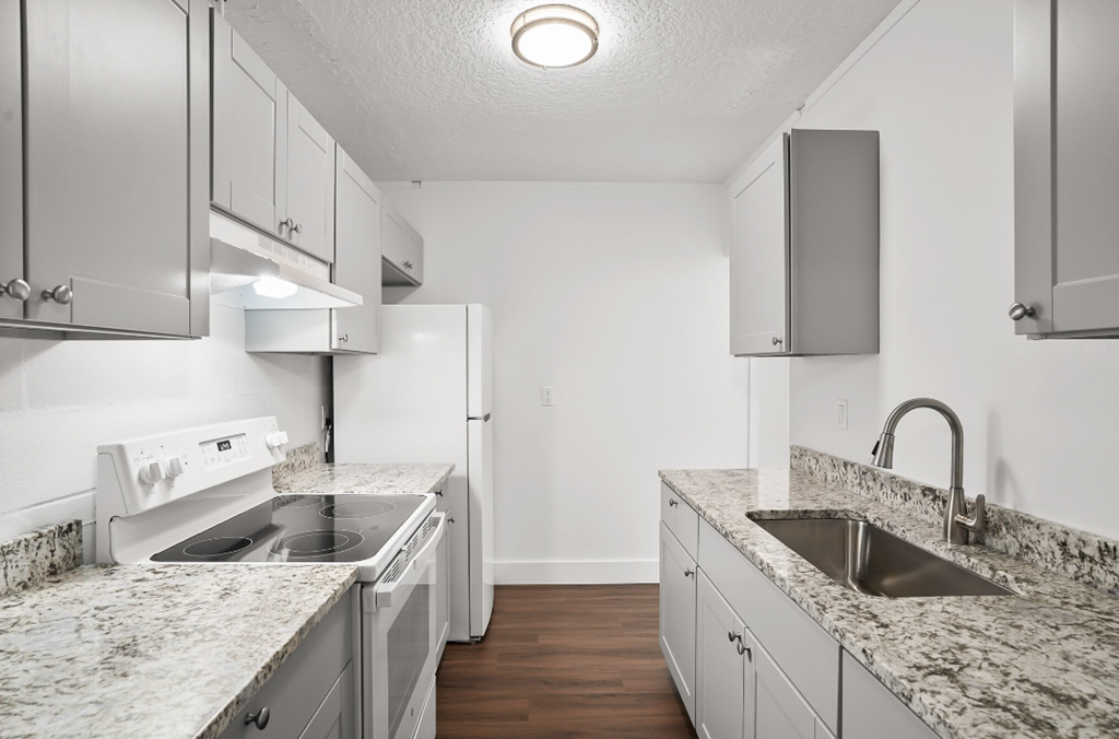 an empty kitchen with granite counter tops and white appliances