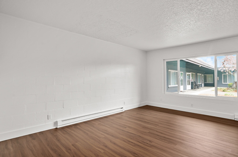 an empty living room with wood floors and a large window