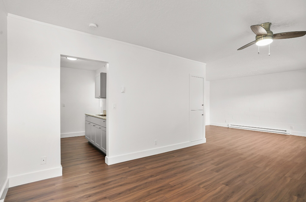 an empty living room with wood flooring and a ceiling fan