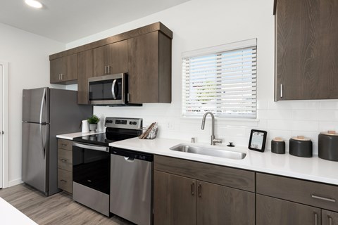 A modern kitchen with dark wood cabinets and stainless steel appliances.