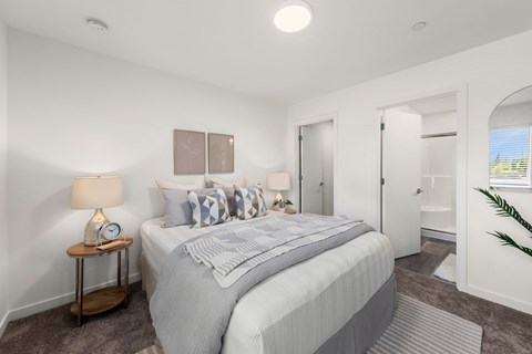 A bedroom with a large bed and a nightstand with a lamp.