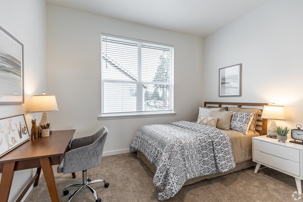 A bedroom with a bed, desk, and chair.