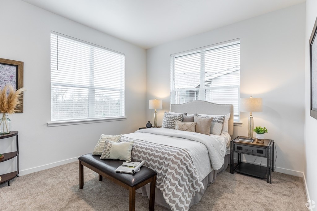 A bedroom with a large bed and a nightstand with a lamp.
