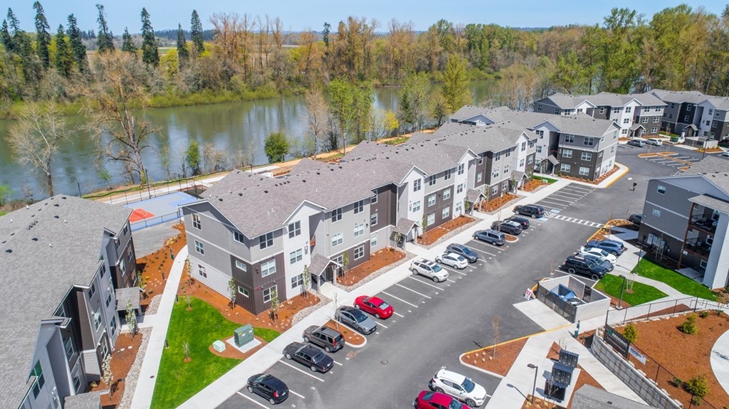 A parking lot in front of a building with a lake in the background.