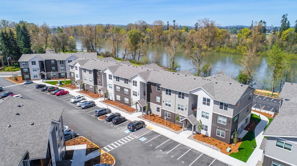 A parking lot in front of a building with a lake in the background.