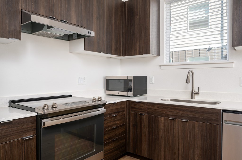 A modern kitchen with dark wood cabinets and stainless steel appliances.