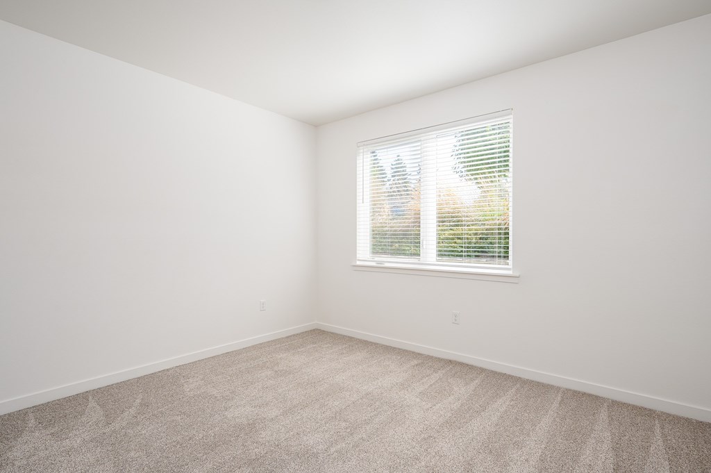 A room with a window and carpeted floor.