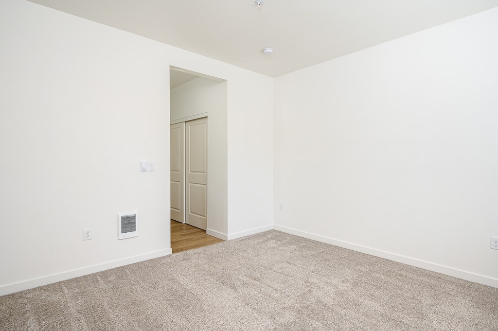 A room with a carpeted floor and a doorway leading to another room.