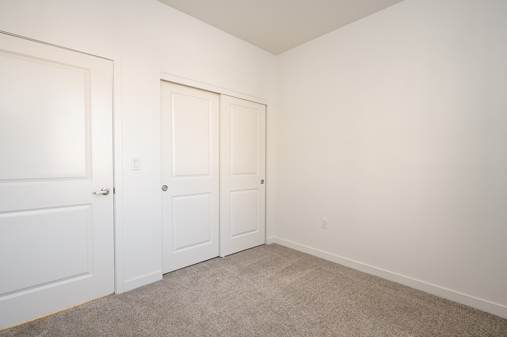 Three white doors in a room with carpeted floor.