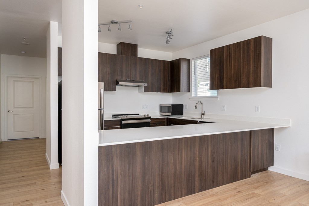 A modern kitchen with dark wood cabinets and a white countertop.