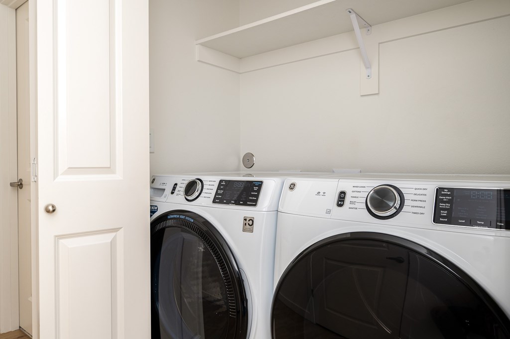 Two white front load washing machines in a laundry room.