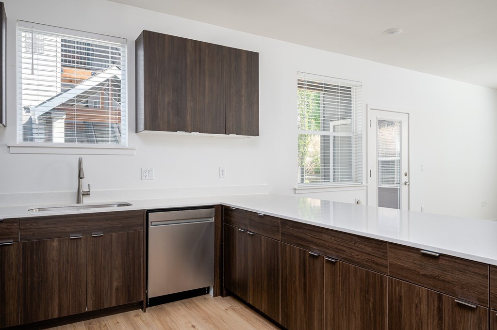 A kitchen with brown cabinets and a stainless steel dishwasher.