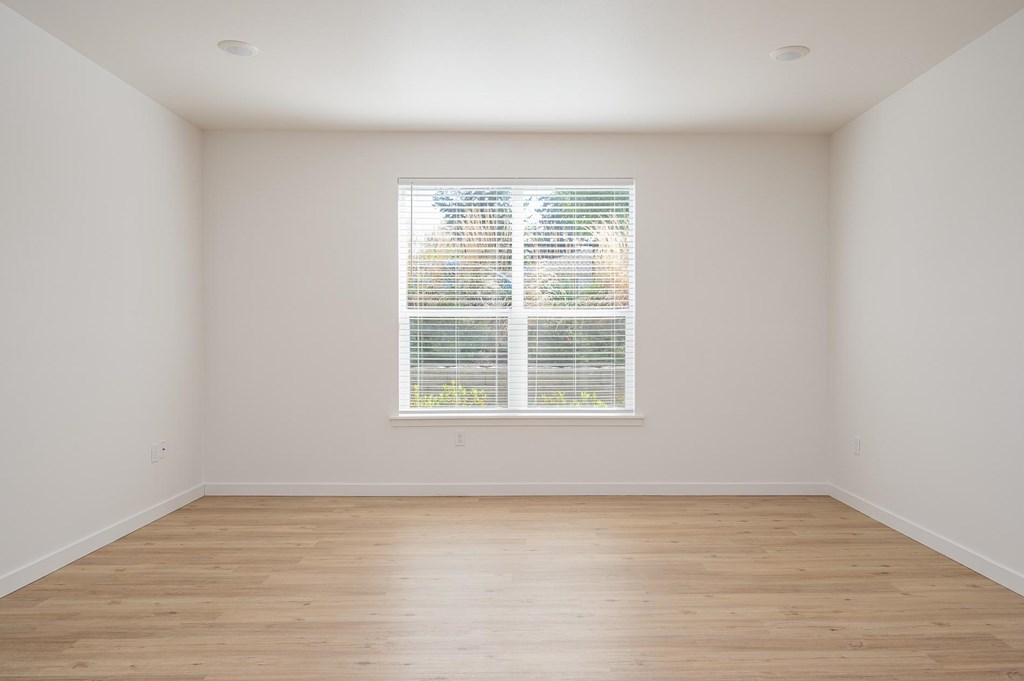 A room with a window and wooden flooring.